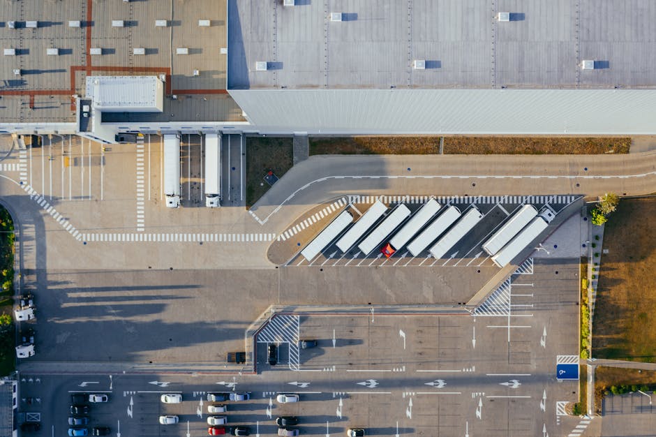 Aerial view of a logistics center with trucks lined up at loading docks, illustrating the coordination hub where freight brokers and forwarders match cargo with carriers.