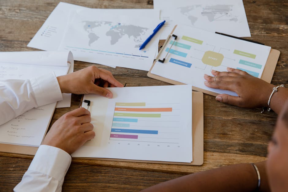 Colleagues in a business meeting reviewing performance charts and growth strategy across a wooden table.