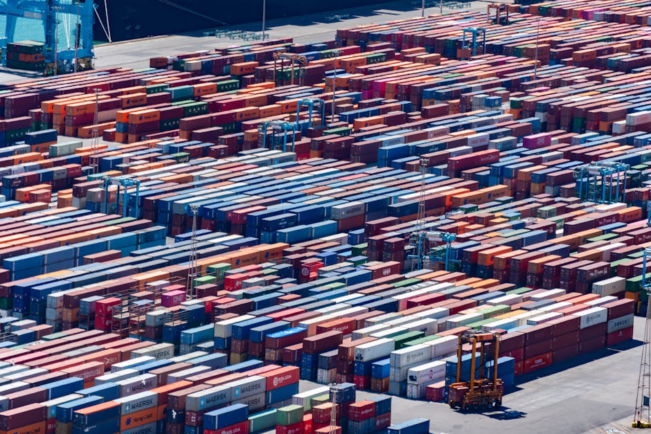 Aerial view of stacked shipping containers at a working port, illustrating the scale of ocean freight operations.